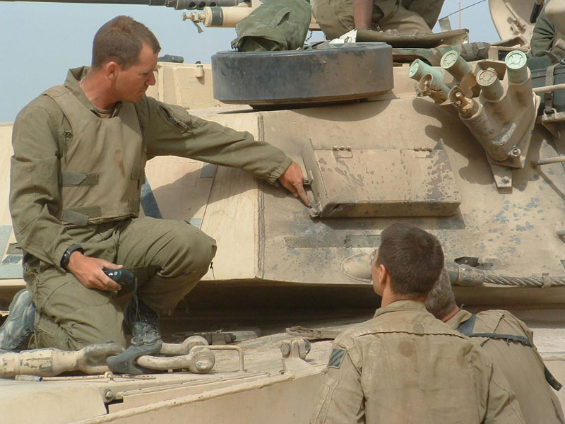 Several men positioned on top/standing next to a US Army tank 